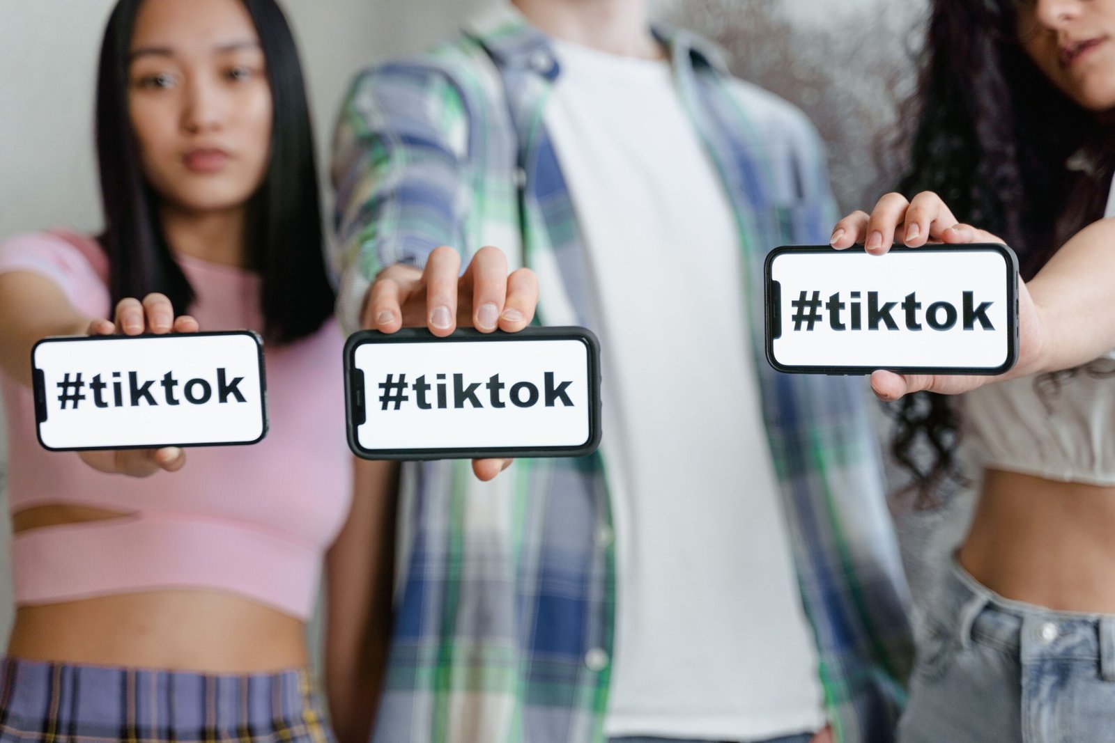 Young adults holding smartphones with TikTok hashtag, showcasing social media engagement.
